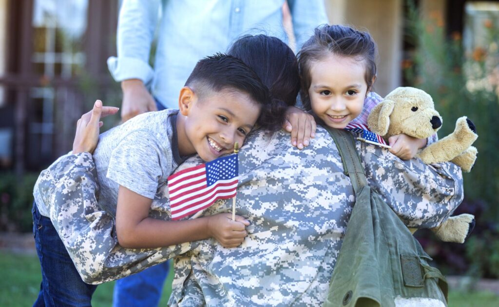 Military parent hugging children